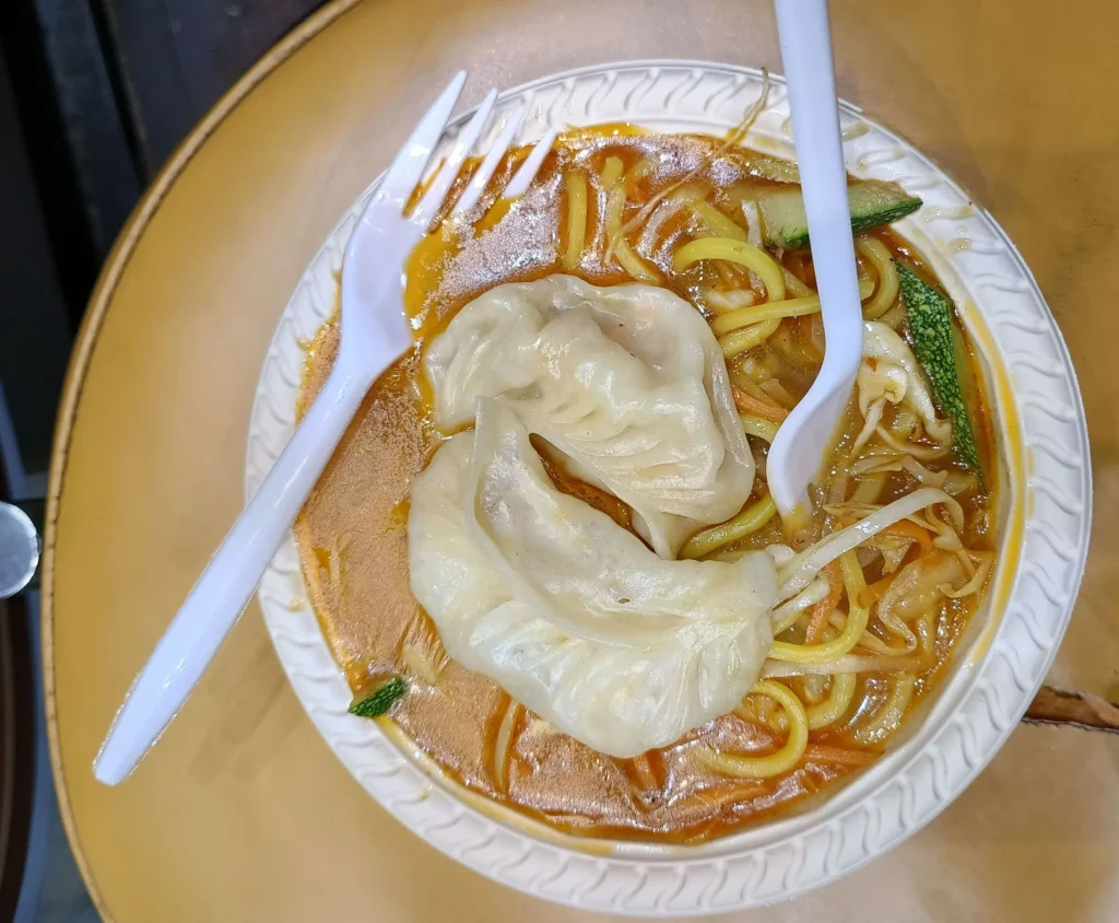 A bowl of traditional Tibetan Thukpa noodle soup with fresh mountain vegetables and meat chunks in Darjeeling